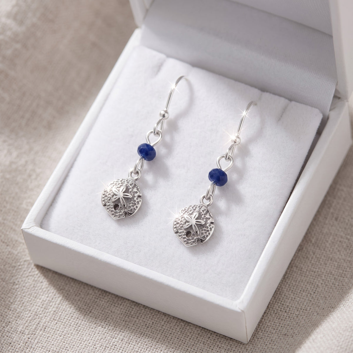 Sterling Silver Dangling Sand Dollar Fishhook Earrings for Women in a white gift box, ready to give