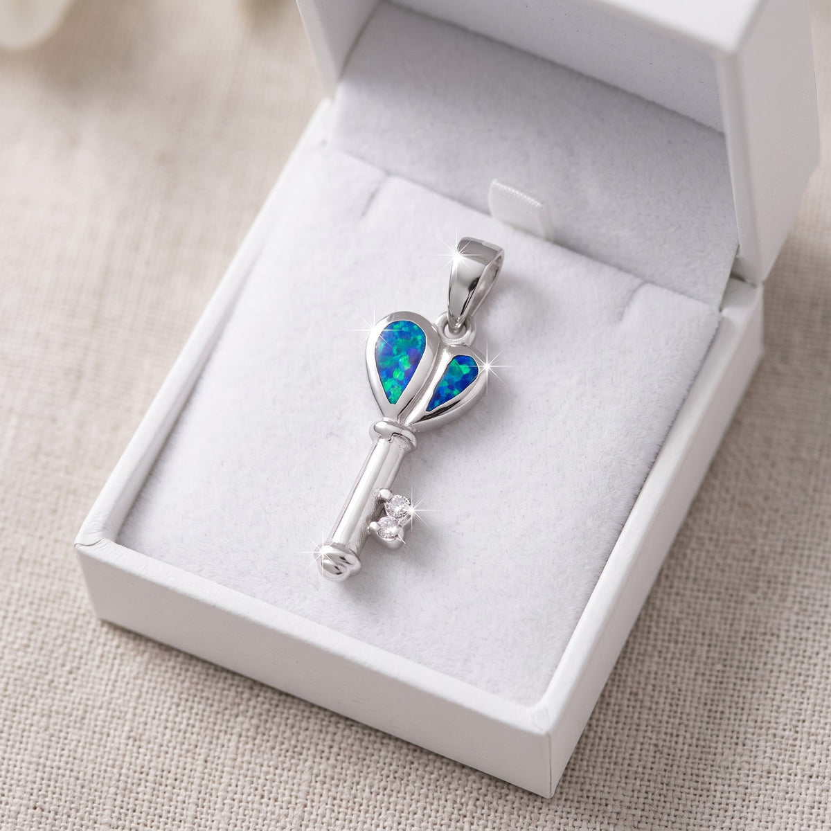 Sterling Silver CZ Created Blue Opal Heart Key necklace in a white gift box, ready to give
