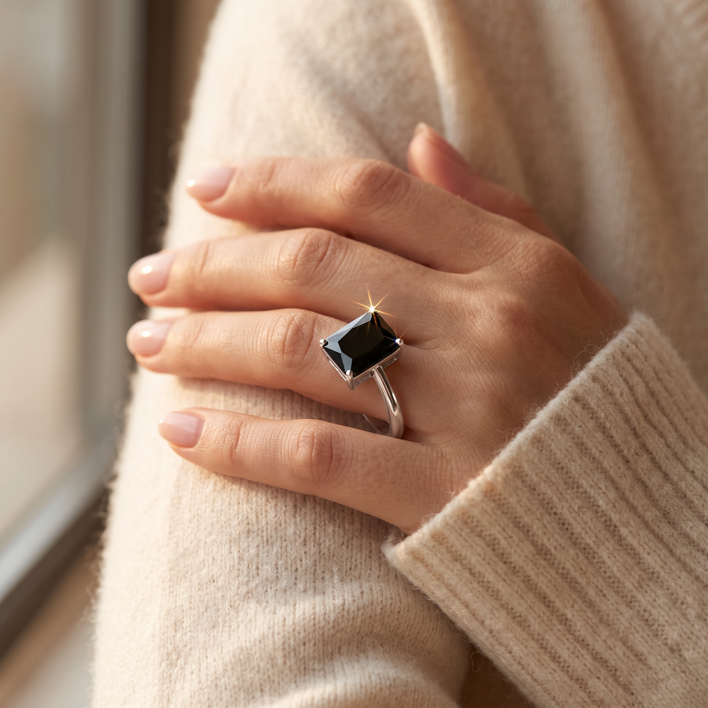 Sterling Silver Solitaire Emerald Cut Black CZ Ring worn on a woman's hand in warm window light