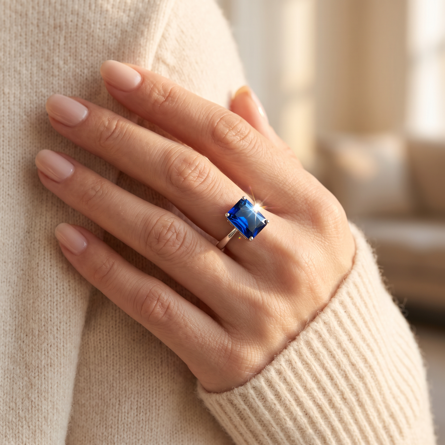Sterling Silver Solitaire Emerald Cut Blue Spinel CZ Ring worn on a woman's hand in warm window light