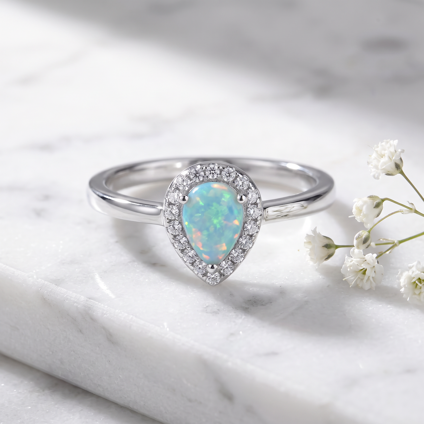 Sterling Silver White Lab Opal Tilted Pear Halo CZ Ring on marble