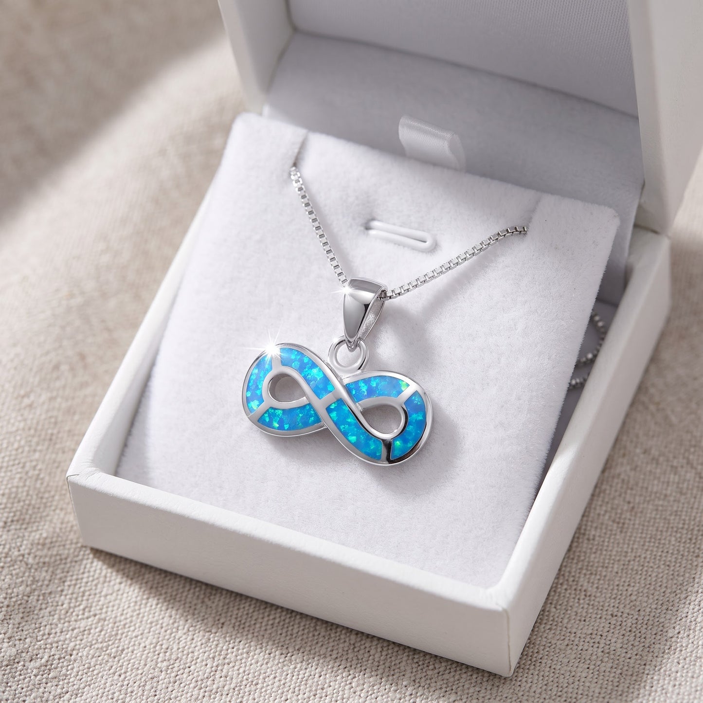 Sterling Silver Created Blue Opal Infinity Necklace in a white gift box, ready to give