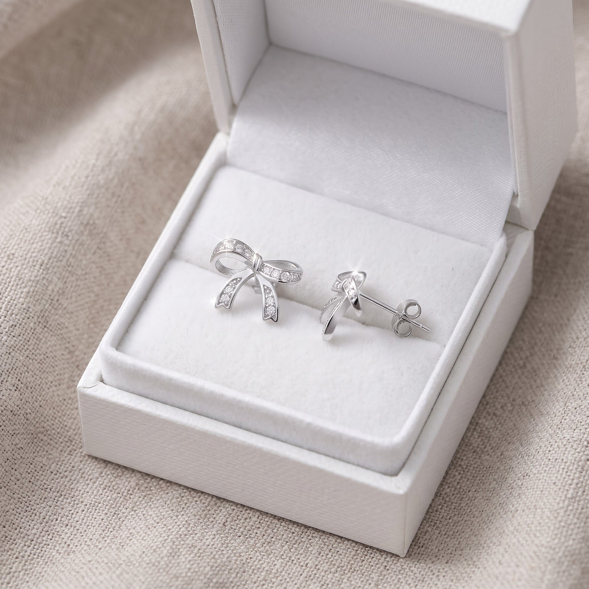 Sterling Silver CZ Ribbon Bow Stud Earrings in a white gift box, ready to give