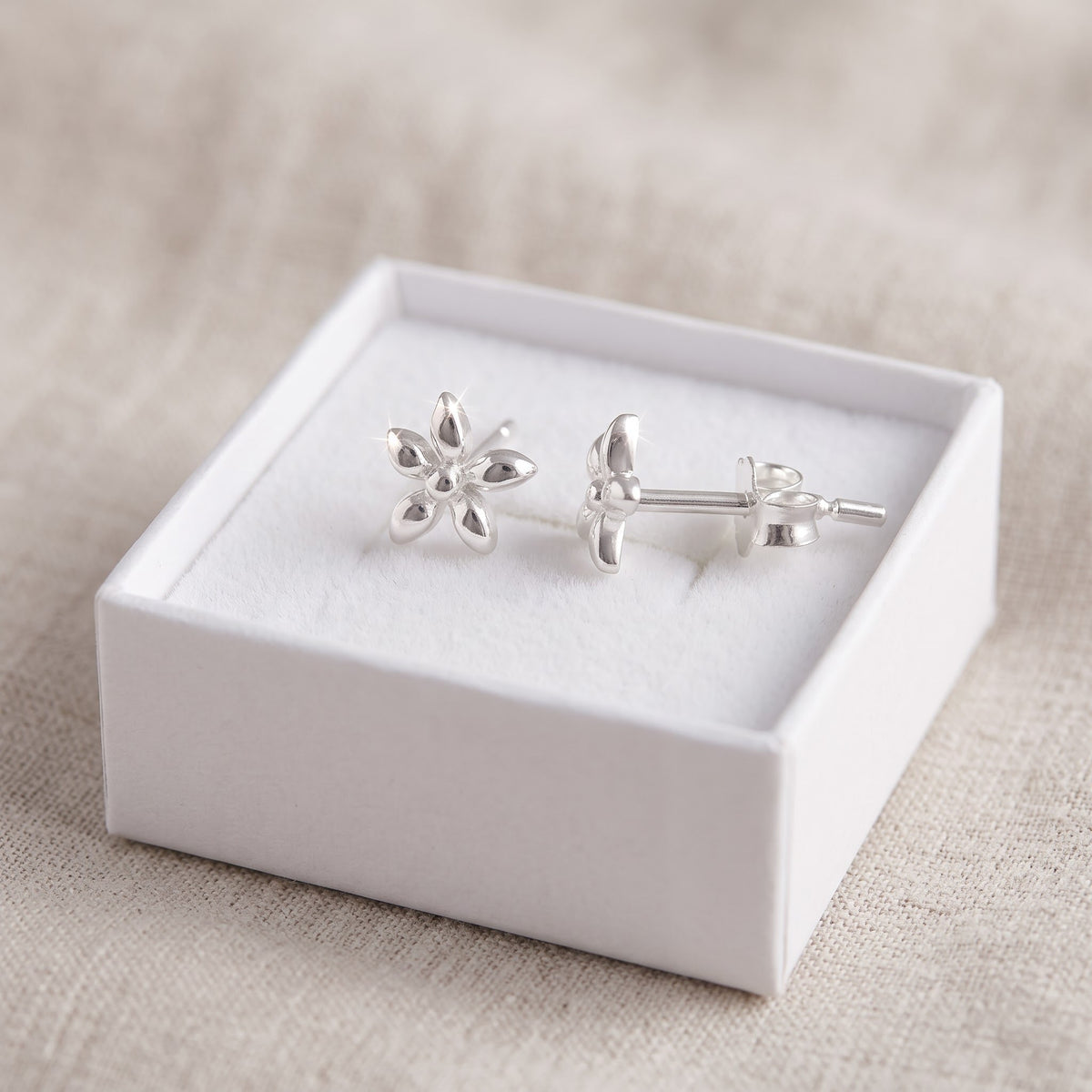 Sterling Silver Girls Tiny Star Flower Stud Earrings in a white gift box, ready to give