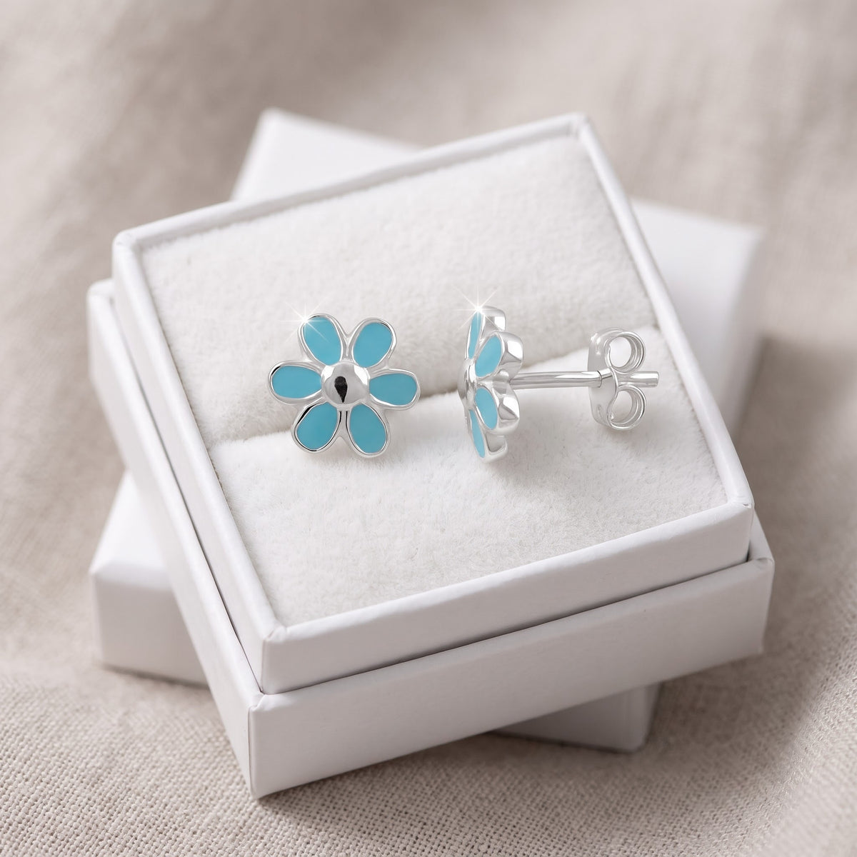 Sterling Silver Girls Dainty Light Blue Daisy Flower Stud Earrings in a white gift box, ready to give