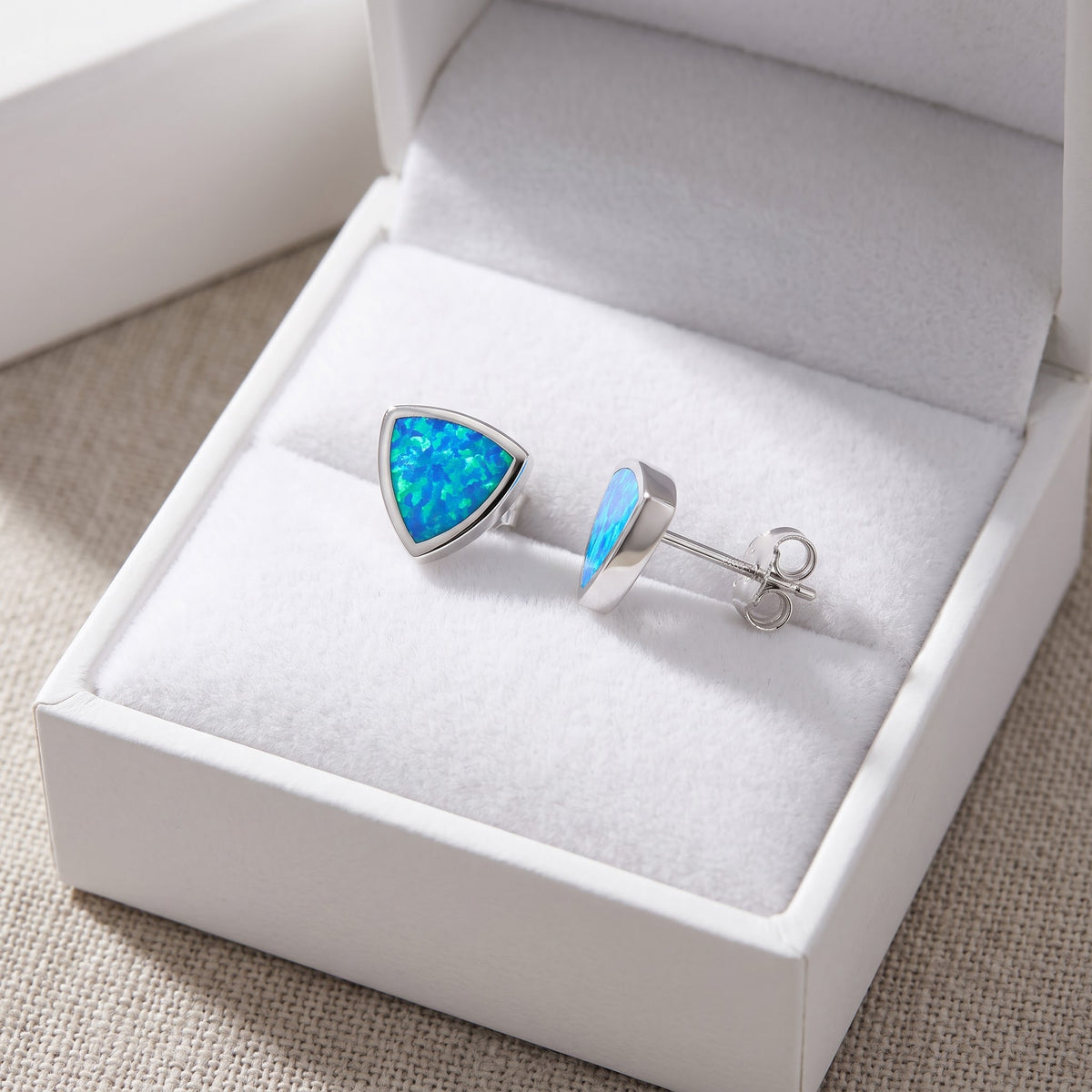 Sterling Silver Girls Created Blue Opal Triangle Stud Earrings in a white gift box, ready to give
