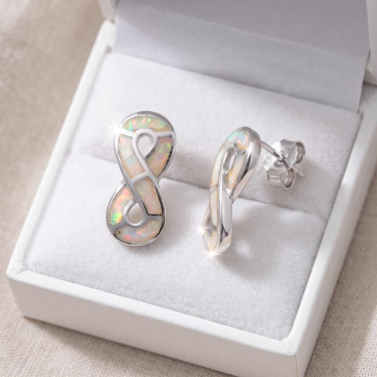 Sterling Silver Girls White Created Opal Infinity Stud Earrings in a white gift box, ready to give